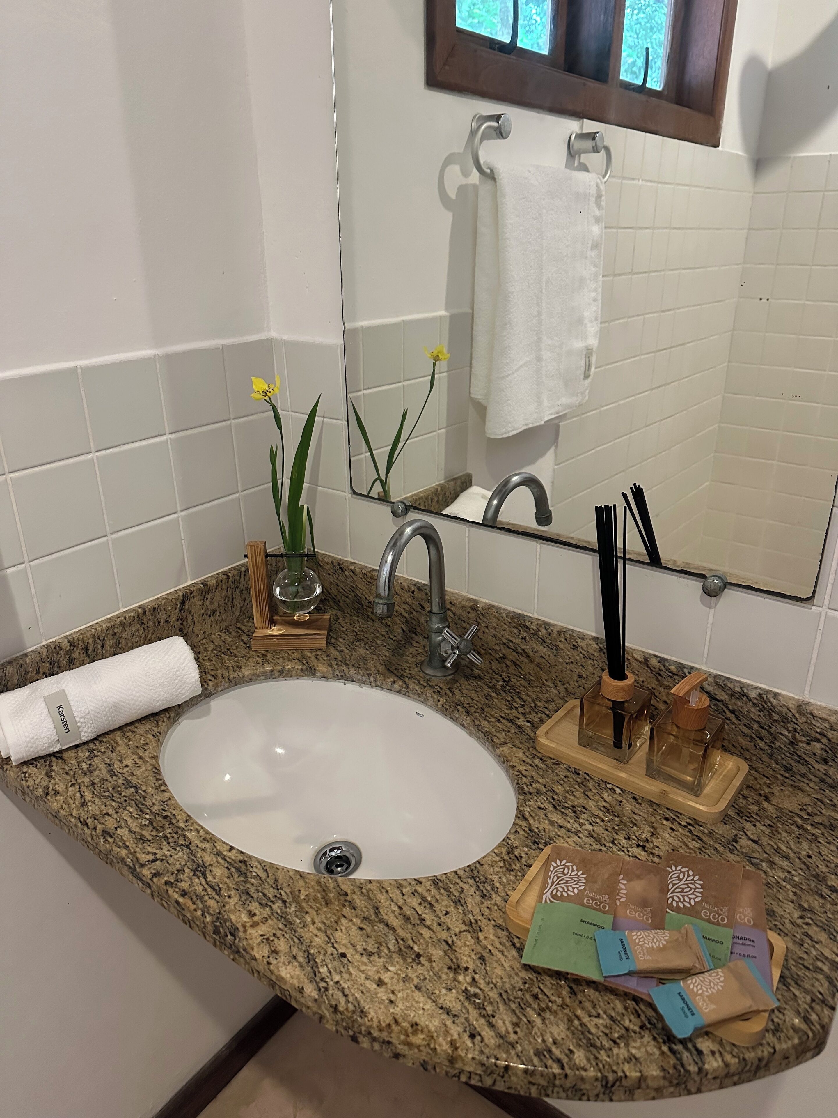 Un baño con encimera de granito, lavamanos blanco, espejo y toallero.