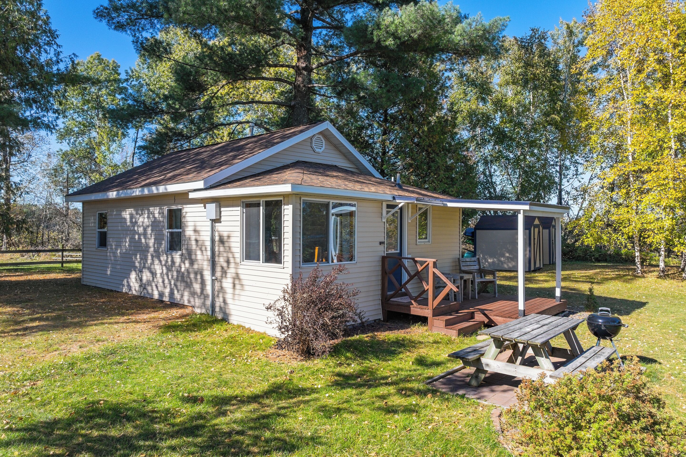 A small, single-story cabin with a porch and a picnic table.