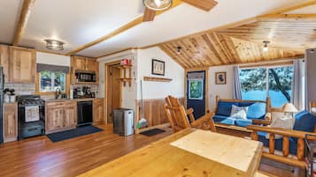 A spacious kitchen with wooden cabinets, a dining area with a wooden table, and a cozy seating area with a view of the outdoors.