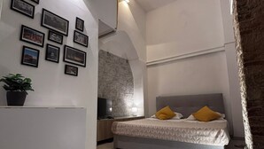 Ein Schlafzimmer mit Bett, Fernseher, einer Steinwand und gerahmten Bildern an der Wand.