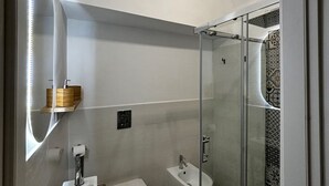 Ein modernes Badezimmer mit einer gläsernen Duschkabine, einem Waschbecken und einem Bidet.