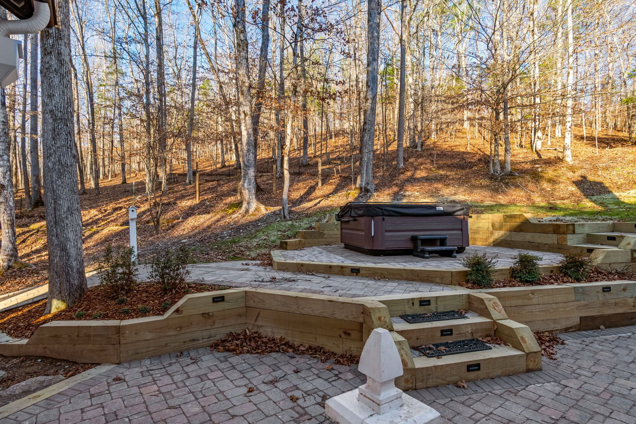 Un espace boisé doté d’une terrasse en bois, d’un jacuzzi et d’une sculpture en pierre.