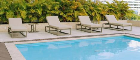Un área junto a la piscina con sillones de descanso.
