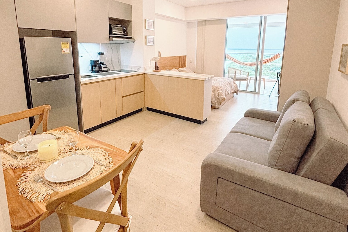 Um espaço compacto para viver, com cozinha compacta, área de refeições e sofá.