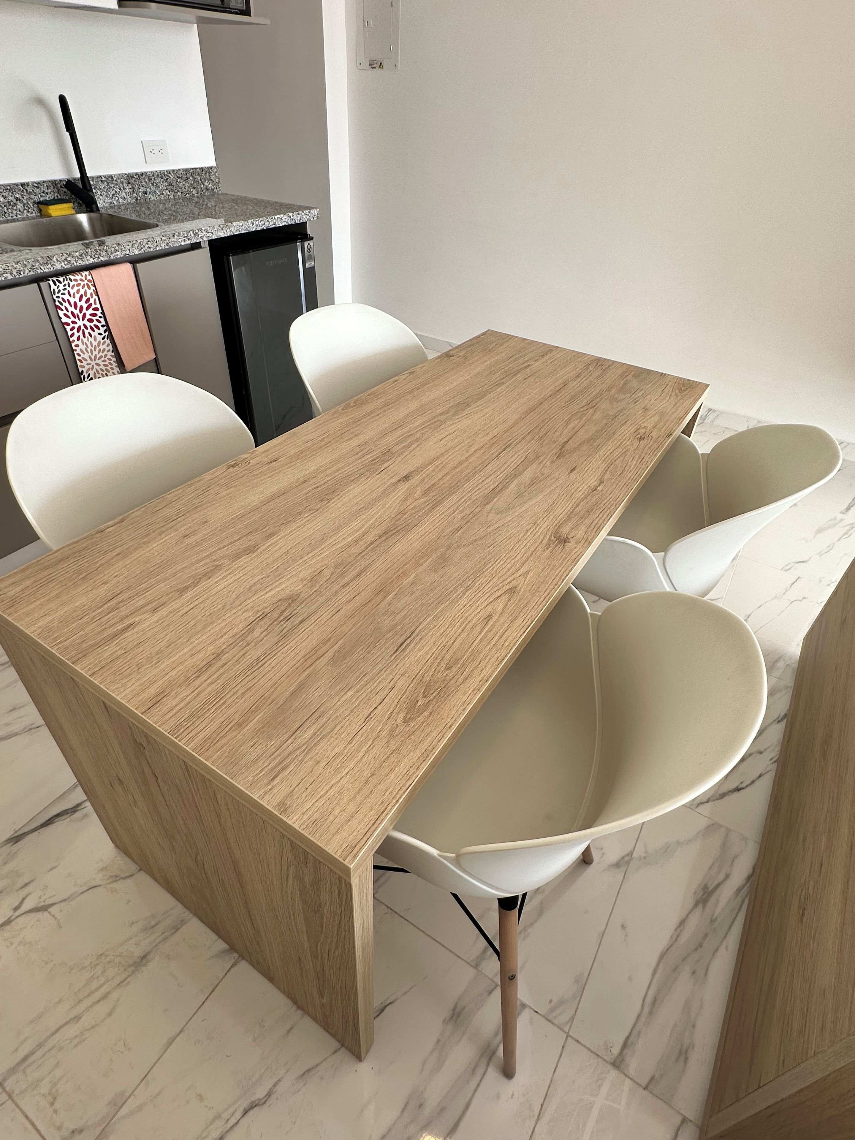 Ein stilvoller Essbereich mit Holztisch und weißen Stühlen.