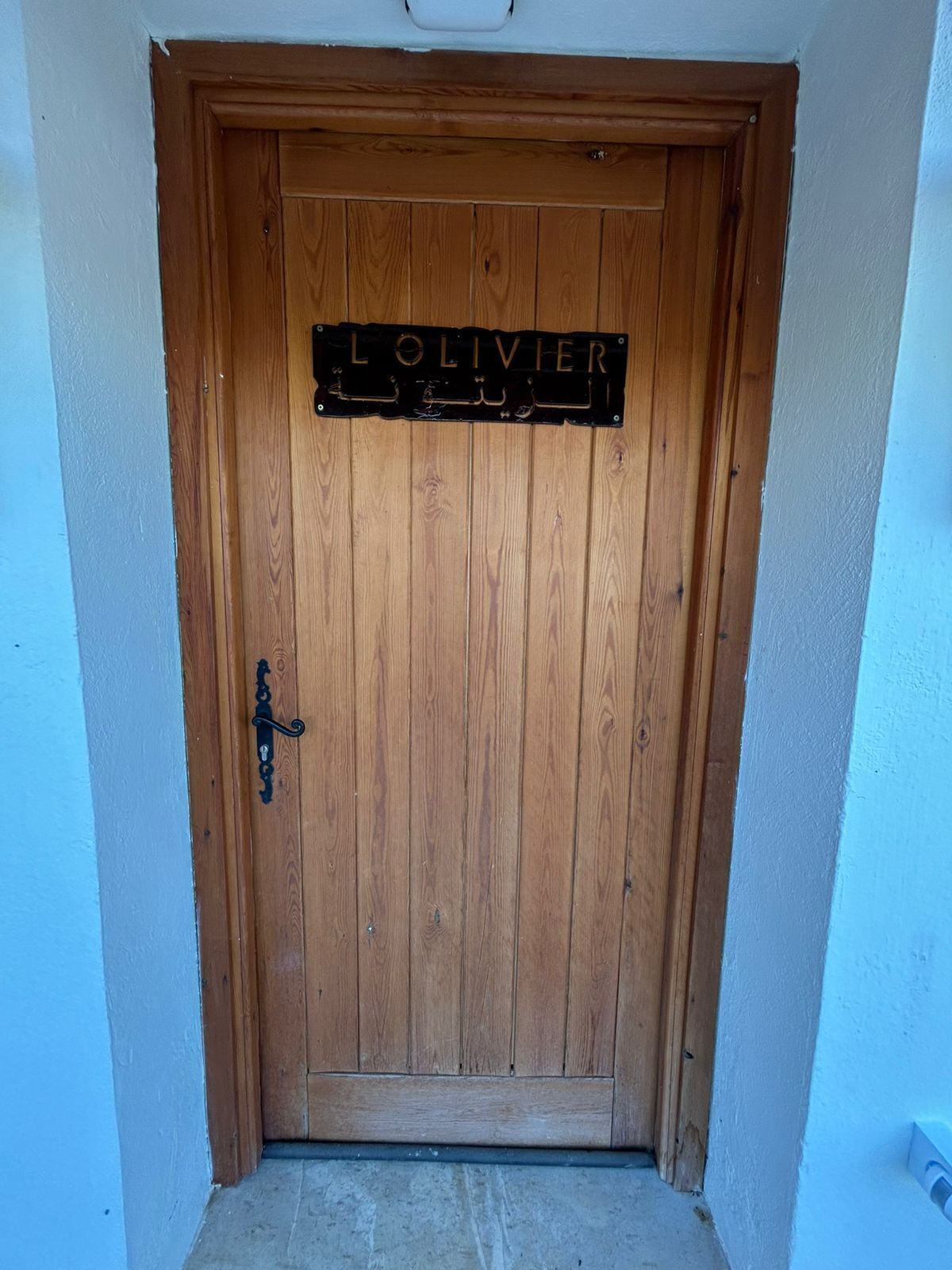 Une porte en bois sur laquelle est fixée une enseigne portant l’inscription « LOLVIER ».