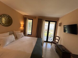 A hotel room with a large bed, a flat-screen TV, a chair, and a balcony with a view. - Dar Nesri (Zaghouan)