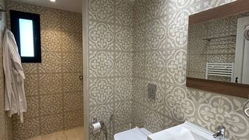 Een badkamer met douche, toilet en wastafel.
