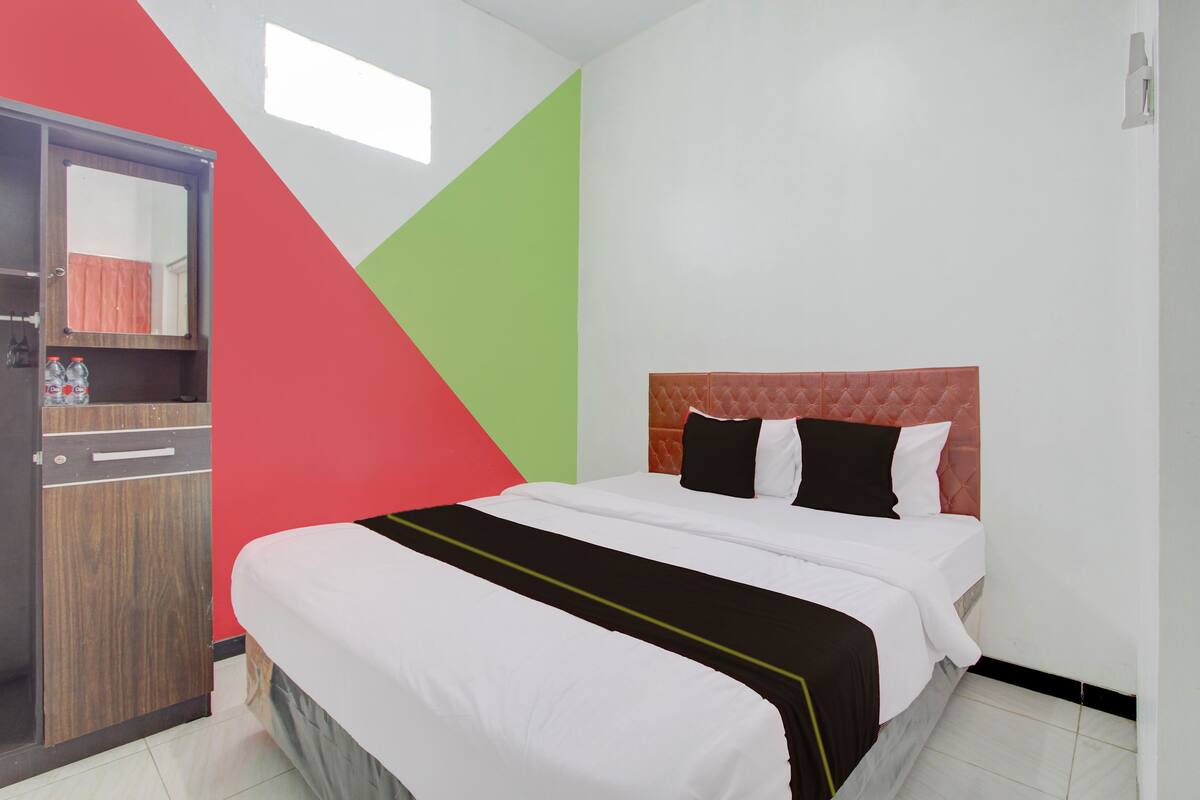 A hotel room with a bed, a wardrobe, and a mirror.