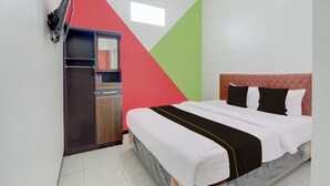 Une chambre à coucher avec un lit, un téléviseur fixé au mur, une armoire et une fenêtre.