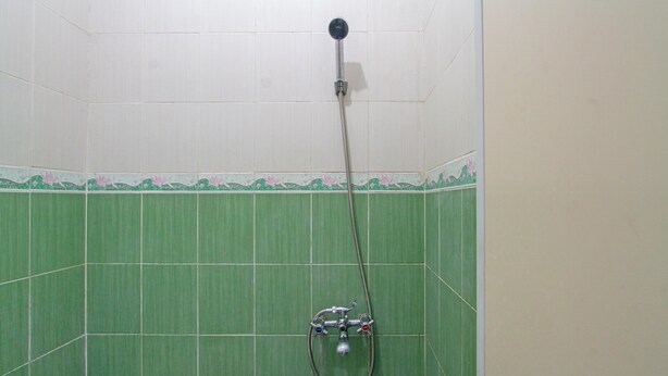 Une douche équipée d’un pommeau de douche à main et d’une pompe à eau portative.