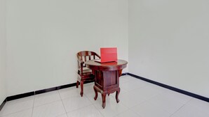 Une pièce avec une chaise en bois et une petite table ronde sur laquelle se trouve un dossier rouge.