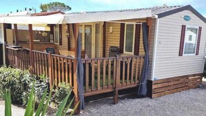 Une maison mobile dotée d’un porche couvert, d’une petite terrasse et d’un espace extérieur clôturé.