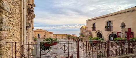 Un patio con edificios de piedra, una valla de metal y plantas en macetas.