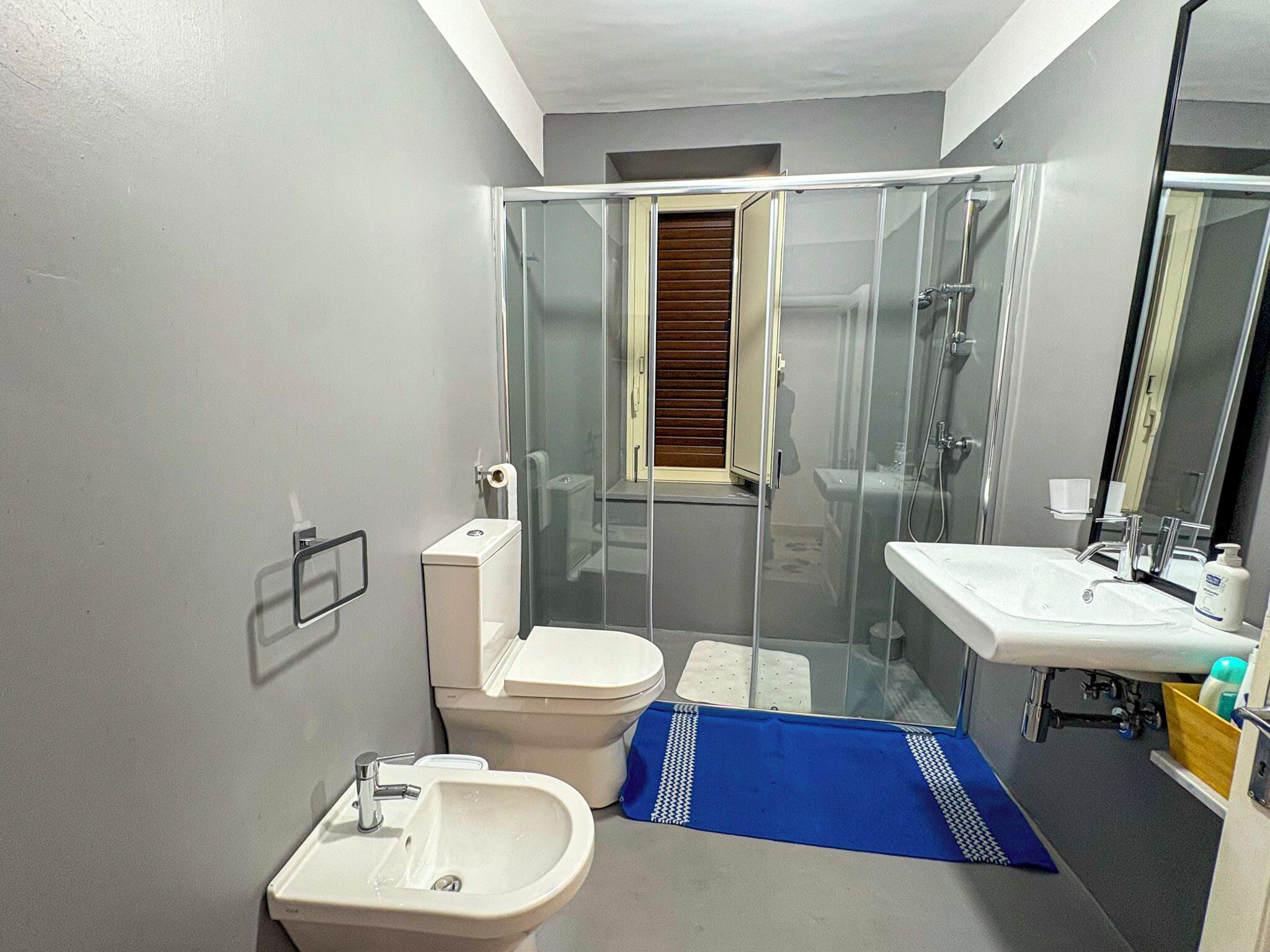 Une salle de bain comprenant des toilettes, un bidet, un lavabo et une douche à parois de verre.