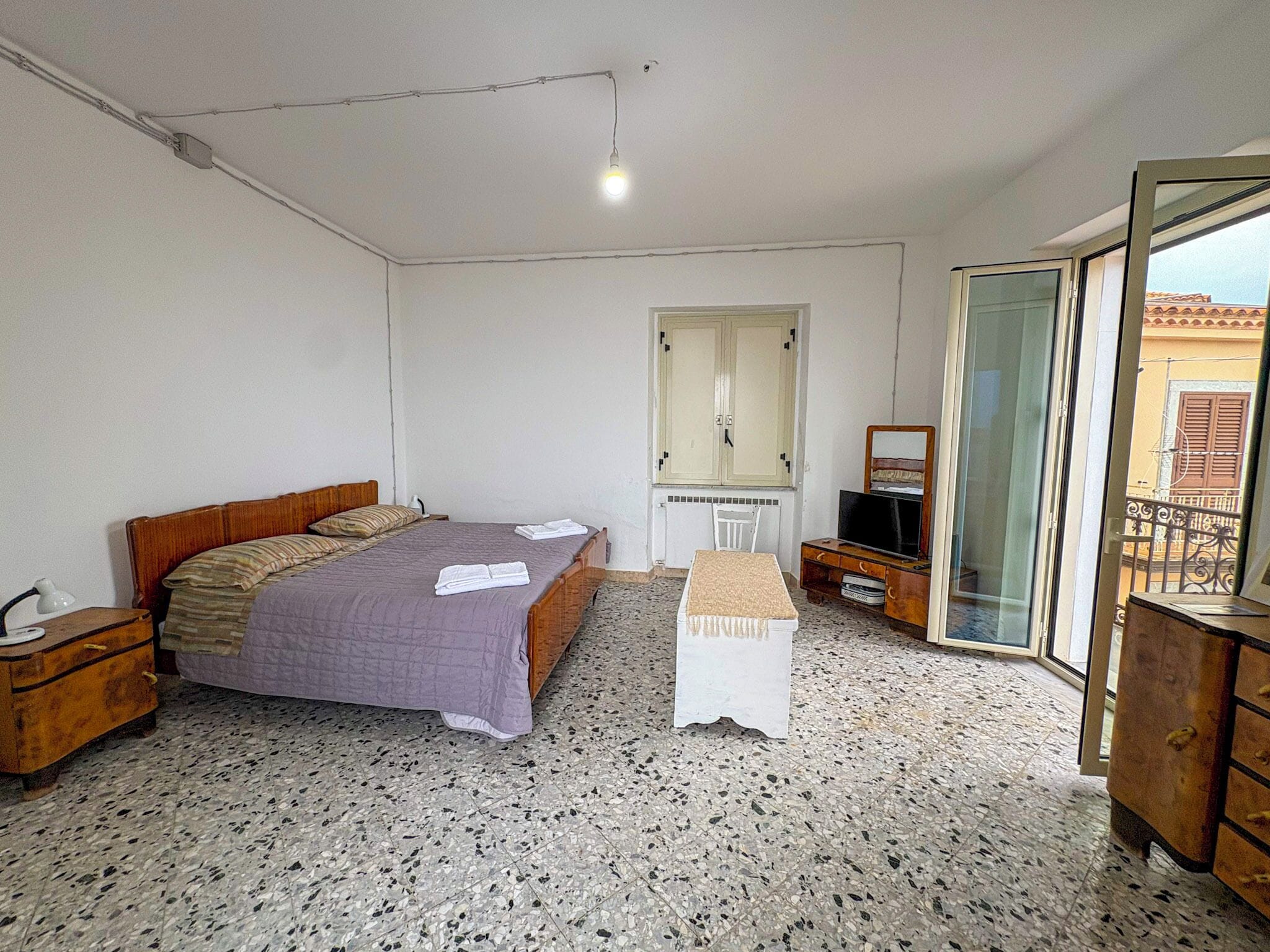 Una camera da letto con un letto, una scrivania, una sedia, una televisione e una finestra.