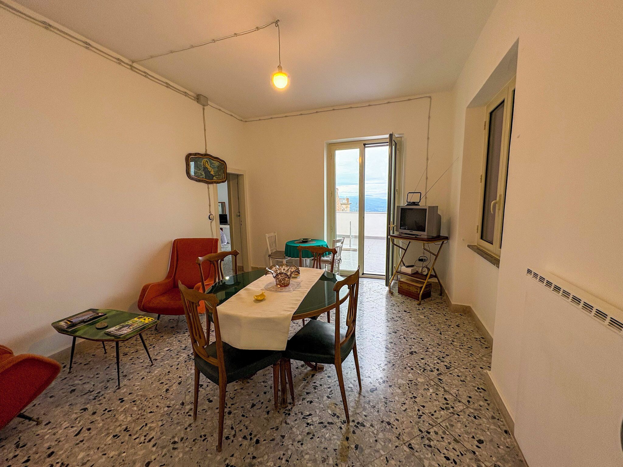 A dining area with a table, chairs, and a television on a stand.
