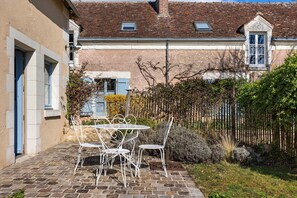 A courtyard with a stone patio, white metal chairs, and a table. - 3-Star House "At the Crossroads of the Castles" (Le Controis-en-Sologne)
