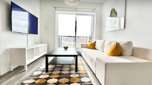 Una sala de estar moderna con un sofá, una mesa de centro, un televisor y un ventanal grande.