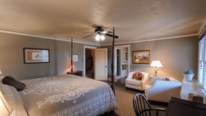 Une chambre à coucher avec un grand lit, une chaise, un bureau et un ventilateur de plafond.
