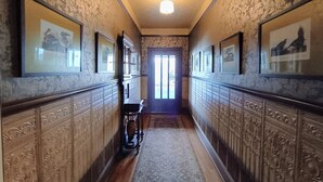 Un couloir agrémenté de boiseries décoratives, de tableaux encadrés et d’un plancher en bois.