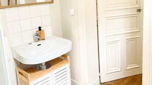 Een badkamer met een wit wastafelmeubel, spiegel en houten kast.