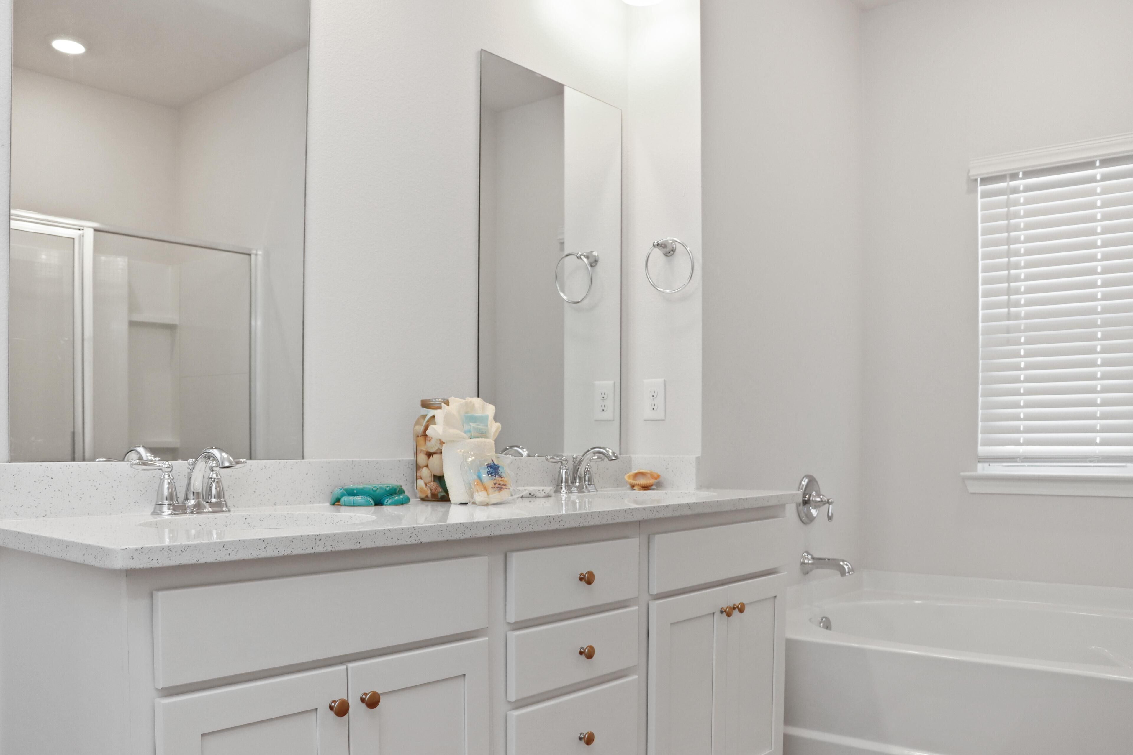 A modern bathroom with a large mirror, a bathtub, and a countertop with toiletries.
