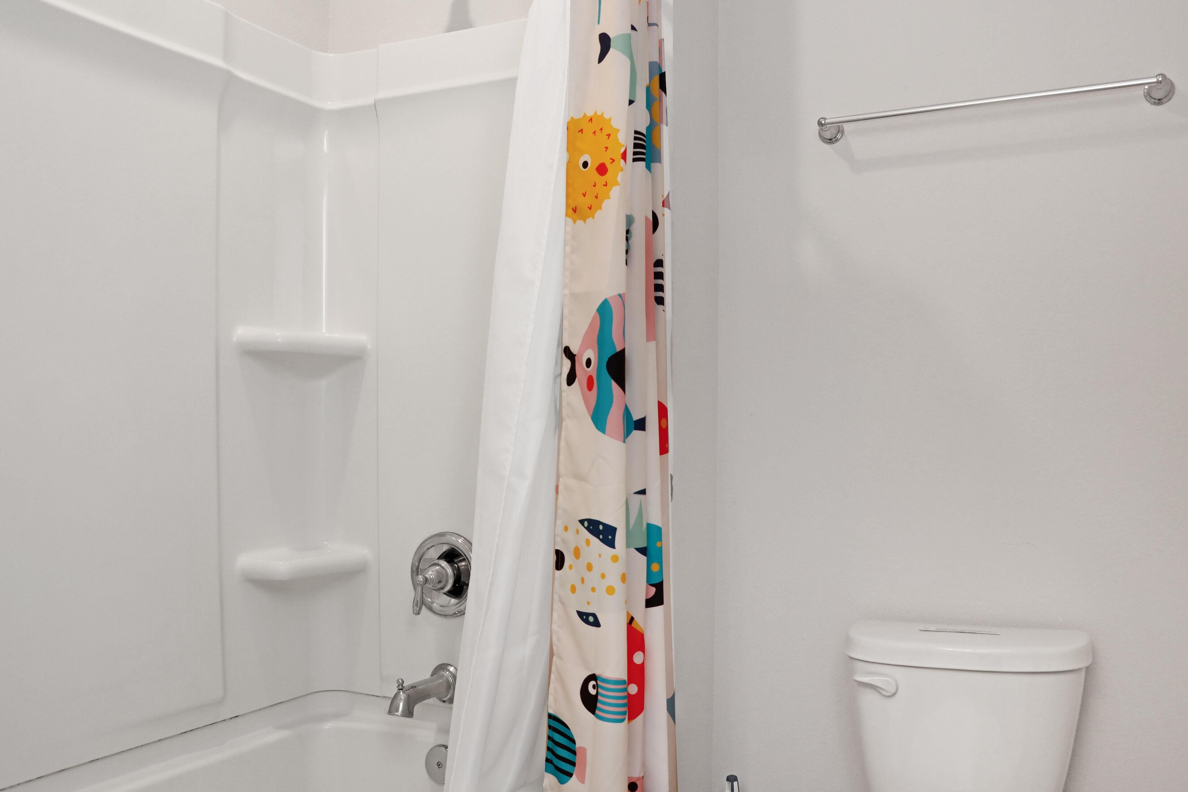 A bathroom with a bathtub, toilet, and a shower curtain with a colorful pattern.