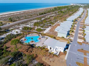 Ein Luftbild eines Resorts mit Schwimmbad, Strand und einer Zufahrtsstraße.