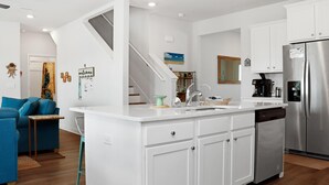 A modern kitchen with white cabinets, a stainless steel refrigerator, and a built-in dishwasher. - Sealavie (Port St. Joe)