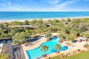 Un resort con piscina, poltrone a sdraio e vista sull'oceano.