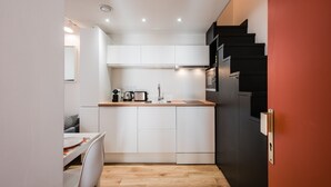 A compact kitchen with white cabinets, a wooden countertop, and a black refrigerator. - SmartStay Perrache - Presqu'île (Lyon)