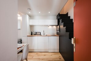Eine kleine Küche mit weißen Schränken, einer Holz Arbeitsplatte und einem schwarzen Kühlschrank.