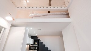 A compact, modern room with a bunk bed, kitchenette, and a staircase leading to an upper level. - SmartStay Perrache - Presqu'île (Lyon)