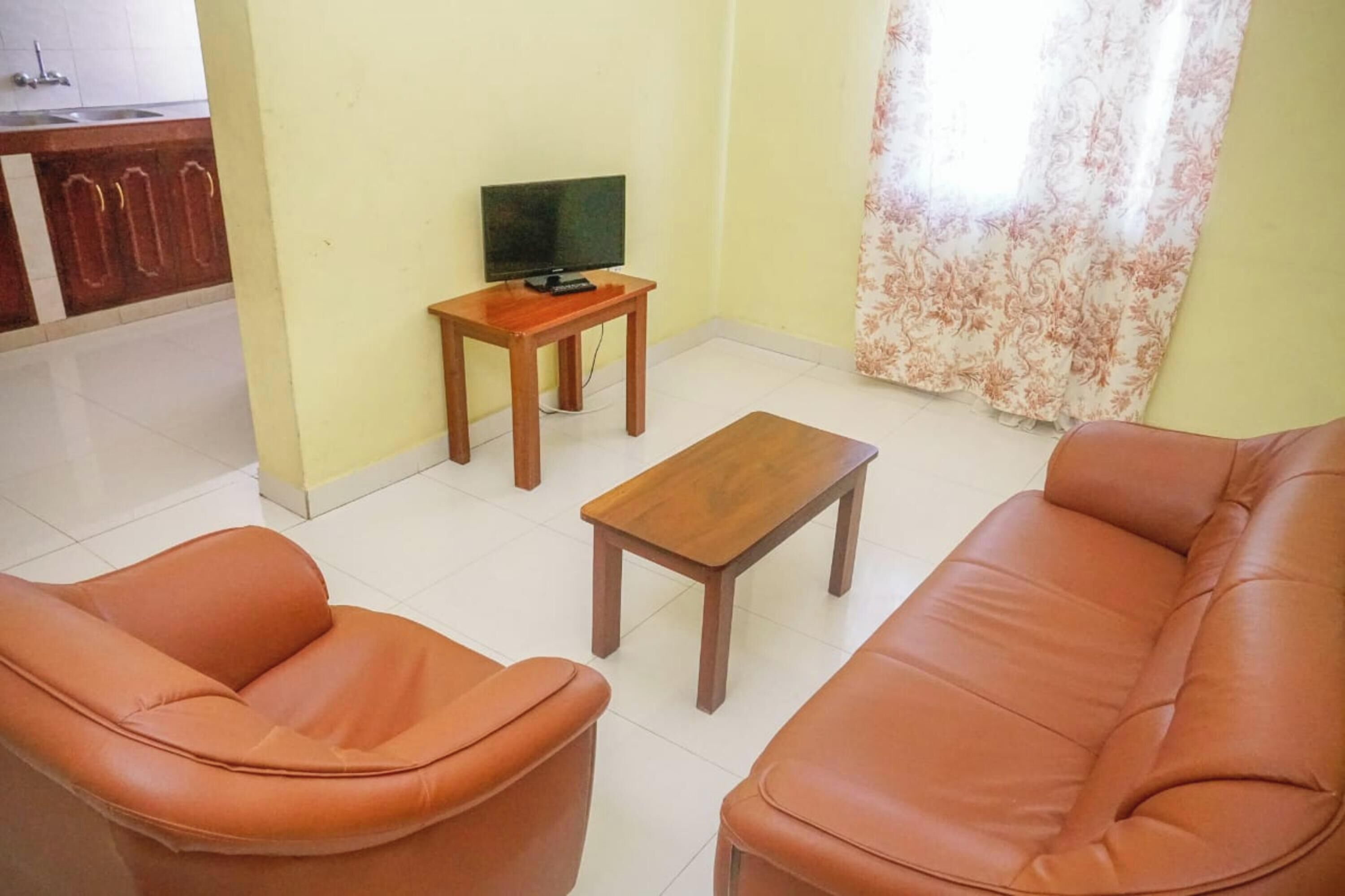 A living room with a sofa, two armchairs, a coffee table, and a TV on a stand.