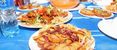 A table set with various dishes, including a plate of potato wedges, a bowl of soup, and a bottle of water.