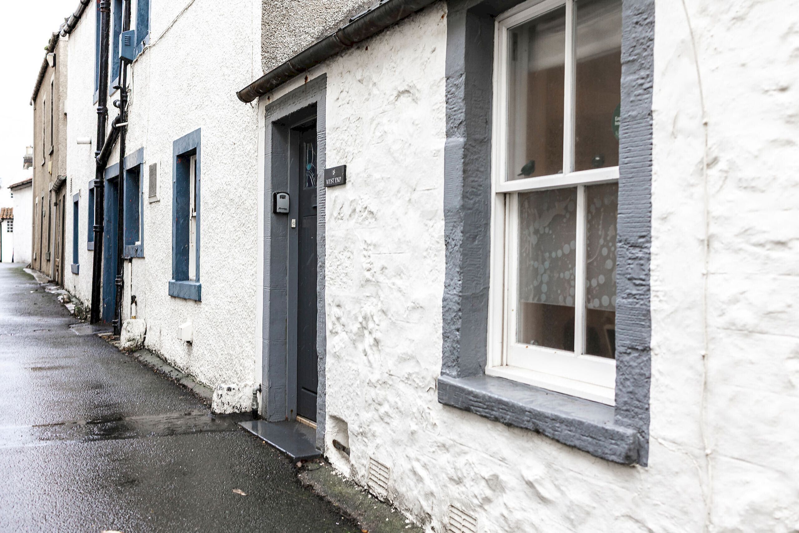 A row of white buildings with dark blue shutters and a narrow street.