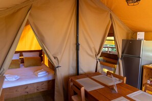 A tented accommodation with a bed, a table, and a refrigerator. - L'Estiva, Safari Tent: 13 hectares, all to yourselves   (Satillieu)