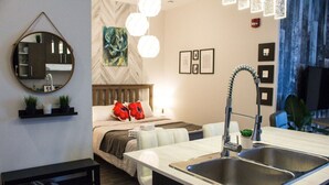 Ein modernes Hotelzimmer mit einem großen Bett, einem integrierten Schreibtisch mit Spüle, einem Spiegel und Kunstwerken an den Wänden.