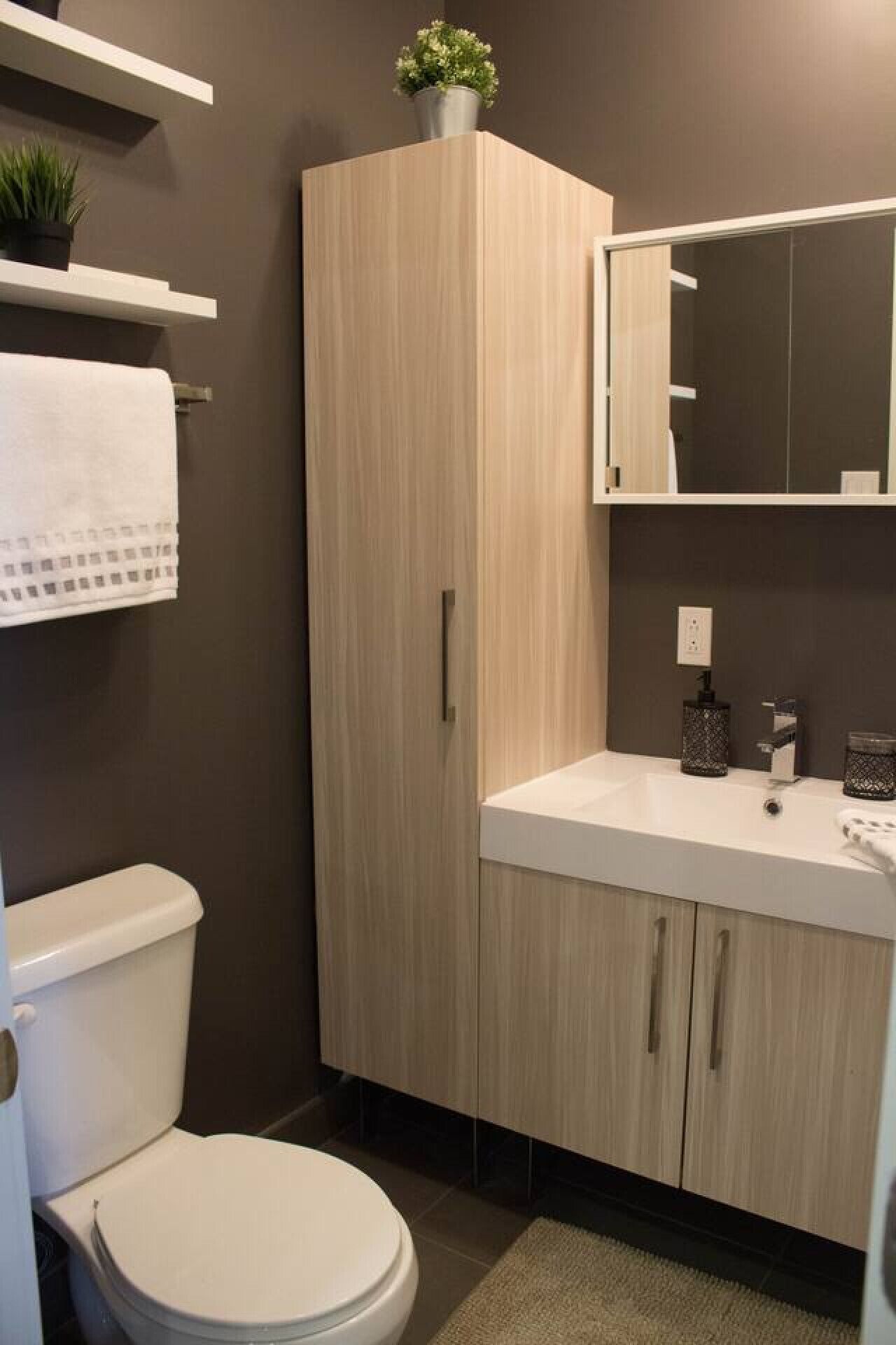 Een moderne badkamer met een toilet, een wastafel en een kast.