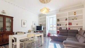 A living room with a white dining table, a sofa, a TV, and a bookshelf. - Vatican Heart 5 pax 2 bath (Roma)