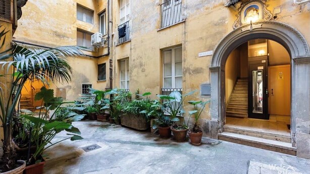 A courtyard with potted plants and a building entrance with a staircase. - Vatican Heart 5 pax 2 bath (Roma)