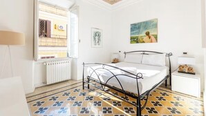 A bedroom with a bed, a window, a radiator, and a painting on the wall. - Vatican Heart 5 pax 2 bath (Roma)
