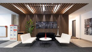 A modern reception area with a cityscape mural, two white sofas, a round table, and a wooden slatted ceiling. - Buchanan *609* - Midtown Luxe Loft + gym (Montreal)