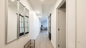 A narrow hallway with a wooden floor, a metal rack, and a door on the right. - Buchanan *609* - Midtown Luxe Loft + gym (Montreal)