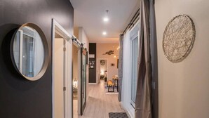 Passadís amb un mirall, una porta i una decoració penjada a la paret.