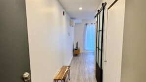 A narrow hallway with a bench, a door with a black frame, and a window with a curtain. - Buchanan *705* - Midtown Luxe Loft + gym (Montréal)