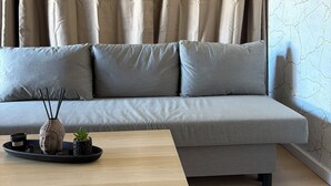 Ein modernes Wohnzimmer mit einem grauen Sofa, einem Holztisch und einer dekorativen Vase.