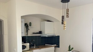 Eine moderne Küche mit weißen Schränken, einer Mikrowelle und einem Spülbecken. Es gibt einen Essbereich mit Tisch und Stühlen.