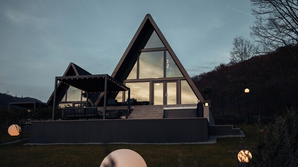 A modern house with a triangular roof, large windows, and a covered outdoor seating area. - Twin Vista A-Frame Cabins (Sovata)